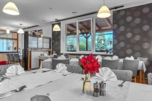 拉贝河畔皇宫镇Hotel Za Vodou的一间用餐室,配有带红色花卉的花瓶桌子