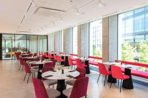 美因河畔法兰克福nhow Frankfurt的餐厅设有桌子和红色椅子以及窗户。