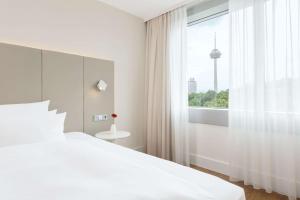 科隆科隆媒体公园NH酒店的白色的卧室设有一张大床和一个窗户