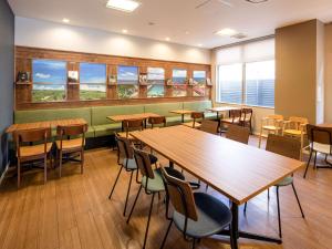 山口新山口康福酒店的餐厅设有木桌、椅子和窗户。