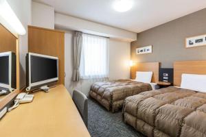钏路北海道康福特酒店的酒店客房设有两张床和一张书桌及电视