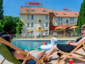 博讷greet Hotel Beaune的两名妇女坐在游泳池旁的草坪椅上
