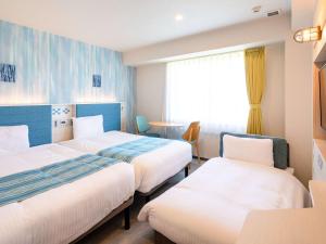 石垣岛Comfort Hotel Ishigaki Island的酒店客房设有两张床和窗户。