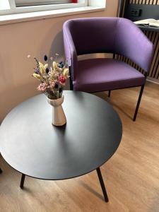 埃斯比约Cabinn Plus Esbjerg的紫色椅子和一张带花瓶的桌子