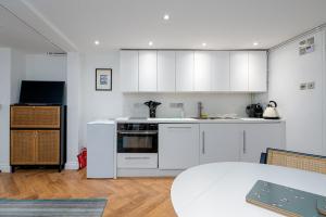 伦敦GuestReady - Charming studio in Hackney的厨房配有白色橱柜和桌子