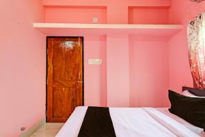 克塔克OYO MAA BHUASUNI RESIDENCY的一间卧室设有粉红色的墙壁、一张床和木门