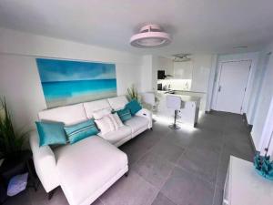 洛斯克里斯蒂亚诺斯Los Cristianos Apartamento cerca de la playa CH94的客厅配有白色沙发和蓝色枕头。