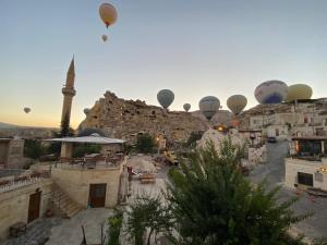 格雷梅Cappadocia Fairy Tale Suites的一群热气球在一座清真寺的城市上空飞行