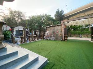 新德里Hotel Lagoona and Banquet Hall的一个带婴儿车的绿色草坪的庭院