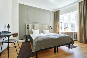 哥本哈根斯卡特托马斯酒店的一间卧室配有一张床、一张书桌和一个窗户。