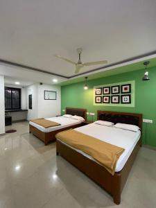马普萨Hotel Sai Advika的绿墙客房的两张床