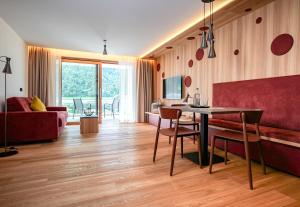 普劳斯Residence & Sportlodges Claudia的客厅配有桌子和红色沙发
