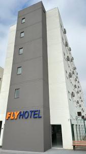 大瓦尔泽亚Hotel Fly - Aeroporto Cuiabá的一座白色的大建筑,上面有飞酒店标志