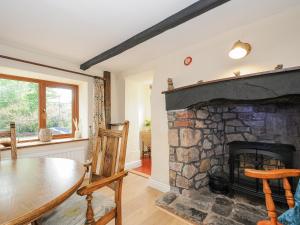 克雷迪顿The Thatched Cottage的客厅设有石制壁炉和桌子。