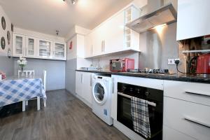 伦敦3 BEDROOM FLAT IN CENTRAL LONDON - REGENTS PARK / BAKER ST的厨房配有白色橱柜、洗衣机和烘干机