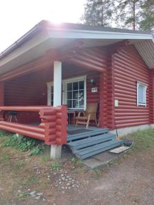 蓬卡哈尤Pankkotupa 16-B的红色小木屋设有门廊和长凳