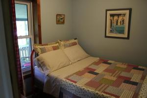莱昂斯黑德Spry Church Cozy Cottage的一间卧室配有一张带被子的床和一扇窗户