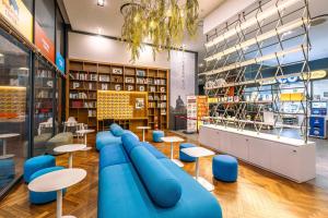 首尔JK盛开酒店的图书馆配有蓝色的桌椅和书架