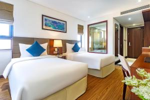 岘港Pavilion Hotel Da Nang的酒店客房配有两张床和一张书桌