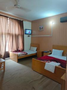 穆扎法拉巴德SEE MOTEL的一间酒店客房,设有两张床和电视