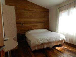 瓦尔迪维亚绿香酒店的一间卧室配有一张木墙床