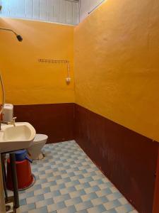 刁曼岛MUKUT CORAL CHALET的黄色的浴室设有卫生间和水槽