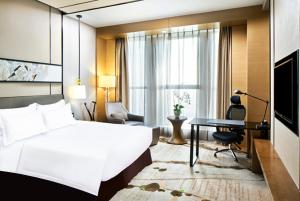 天津天津梅江中心皇冠假日酒店的配有一张床和一张书桌的酒店客房