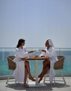 利迈纳里亚360ᵒ Luxury View Collection - Adults Only的两个白人女人坐在餐桌旁吃着食物