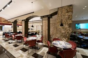 巴塞罗那加泰罗尼亚加泰罗尼亚广场酒店的一间带桌椅和石墙的餐厅