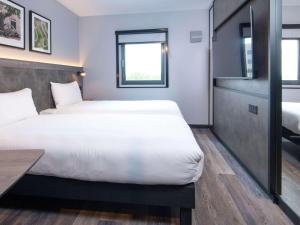 克劳利ibis Styles London Gatwick Airport的酒店客房设有两张床和一张桌子。