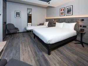 克劳利ibis Styles London Gatwick Airport的酒店客房,配有两张床和椅子