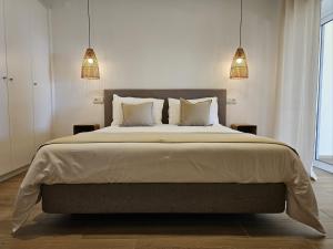 Eira do ChãoParaíso Azul的一间卧室配有一张带两个灯的大床