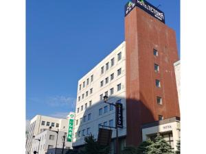 旭川HOTEL TETORA ASAHIKAWA EKIMAE - Vacation STAY 91488v的一座高大的砖砌建筑,上面有标志