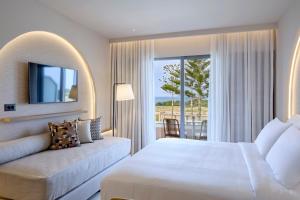 马斯蒂查里Ammos Luxury Resort的一间卧室配有一张床、一张沙发和一个窗口