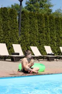 斯基希德尼萨СПА-Готель "RESPECT"的坐在游泳池旁的地面上的男孩
