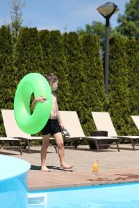 斯基希德尼萨СПА-Готель "RESPECT"的站在一个绿环游泳池旁的年轻人