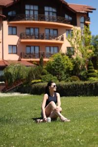 斯基希德尼萨СПА-Готель "RESPECT"的坐在房子前面的草上的一个女人