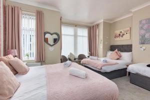 布莱克浦Friends Hotel的一间卧室配有两张带粉色和白色床单的床