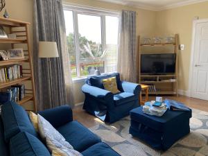CarlowayTigh-na-Greine的客厅配有蓝色的家具和大窗户