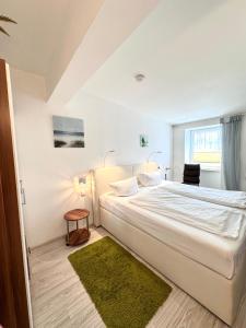 塞巴特阿尔贝克舒尔茨旅馆的白色卧室设有一张绿地毯的大床