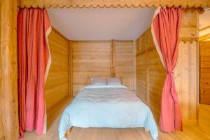 里雾诗Le Prarion 63B - Happy Rentals的木制房间的床,有红色窗帘