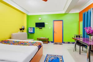 BāghdograFabHotel Relax的一间卧室拥有色彩缤纷的墙壁,配有一张床和一张书桌