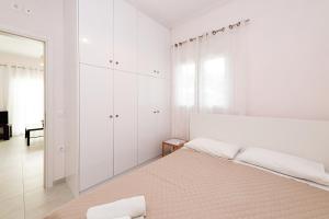 古维亚Lazaros apartments的白色卧室设有一张大床和镜子