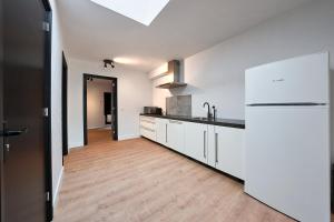埃因霍温The Vault - Eindhoven - by T&S的厨房铺有木地板,配有白色橱柜。