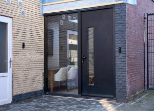 埃因霍温The Vault - Eindhoven - by T&S的砖砌建筑上带桌子的黑色门