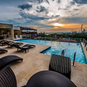 巴兰卡韦梅哈Hotel Súper Estrellas的一个带椅子的游泳池,享有日落美景