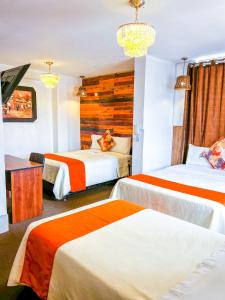 阿亚库乔Ayacucho Plaza的酒店客房带两张床,带橙色和白色的床单。