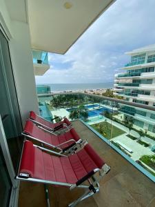 卡塔赫纳APARTAMENTO MORROS922 LA BOQUILLA con acceso directo a la Playa的海景阳台上的红色椅子