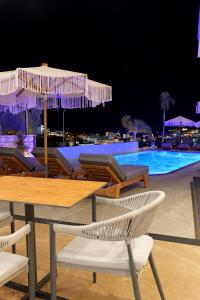 卡萨米尔Ori Mare Hotel的游泳池旁配有遮阳伞的桌椅