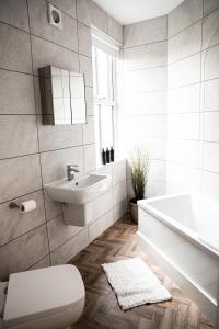 阿什顿下安林恩Urban Loft Apartment • 2 Bedroom • Manchester的浴室配有卫生间、盥洗盆和浴缸。